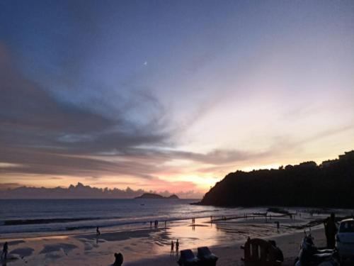 a sunset on a beach with people on the sand at Leon Hide Out Guest House in Vasco Da Gama