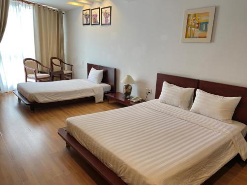 a bedroom with two beds and a table and chairs at Kim Tho Hotel in Can Tho