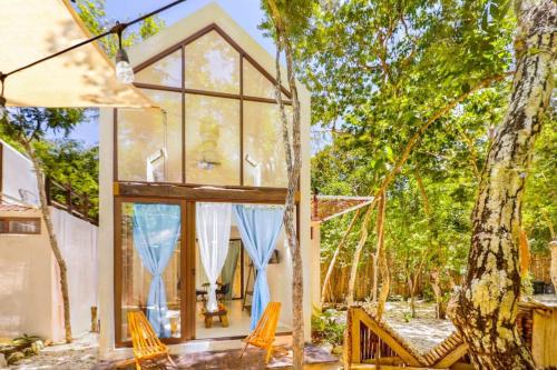 a house with a large window and some chairs at Loft Cabin in Cenote Dos OjOs Natural Park Tulum, Pool, WIFI, AC in Tulum