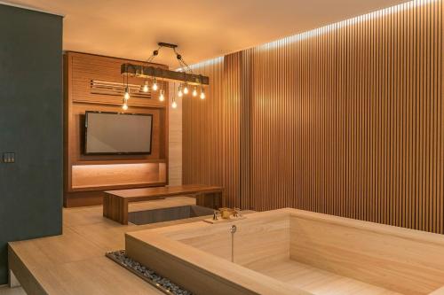 Yeonhwamun Hotel Yeongdeok في Yŏngdŏk: حمام مع حوض استحمام وتلفزيون على الحائط