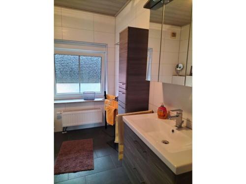 een badkamer met een wastafel, een bad en een raam bij Holiday apartment Stephanie Ahlborn in Schönhagen