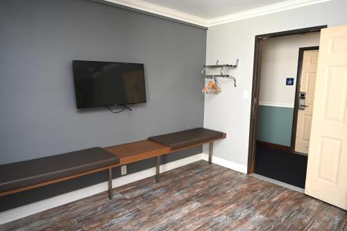 a room with a bench with a flat screen tv on the wall at Hollywood Stars Inn in Los Angeles