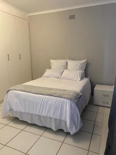 sypialnia z łóżkiem z białą pościelą i poduszkami w obiekcie Vaal Self Catering close to Vaal Mall and Aquadome w mieście Vanderbijlpark