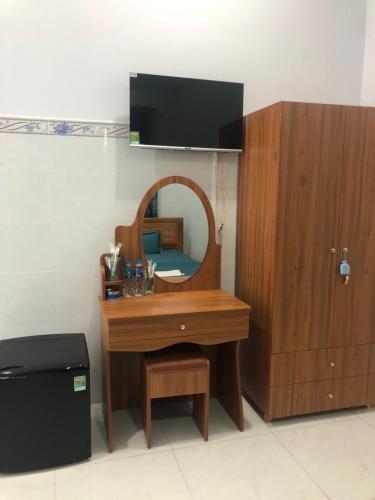 a wooden desk with a mirror and a dresser at Khách Sạn Vinhomes Huỳnh Hotel in Ben Tre