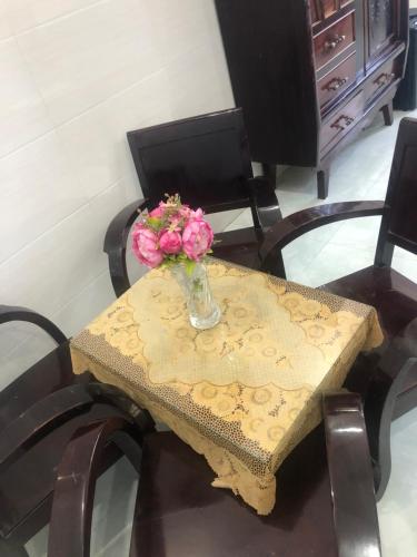 une table avec un vase avec des fleurs roses dans l'établissement Khách Sạn Vinhomes Huỳnh Hotel, à Ben Tre