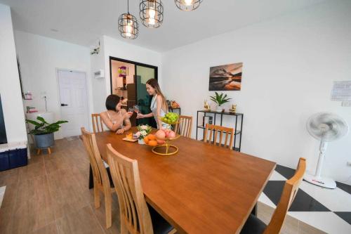 a woman taking a picture of a child sitting at a dining room table at Baan Khongkwan Pool villa Khaoyai Pakchong in Pak Chong