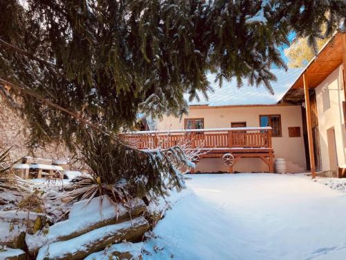 a house with a wooden bench in the snow at Tradičná kopaničiarska chalupa in Košariská-Priepasné