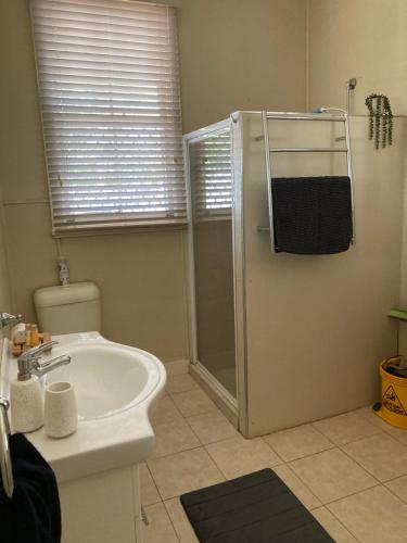 a bathroom with a shower and a white sink at Maeville Cottage in Broken Hill