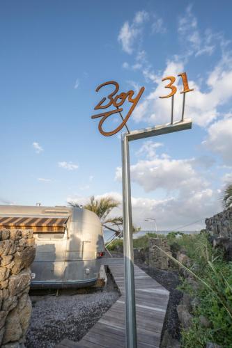 a sign for a rv parked next to a building at BeachBoys - Retro Caravan AirStream in Jeju