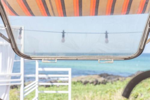 a view of the ocean from a bus window at BeachBoys - Retro Caravan AirStream in Jeju