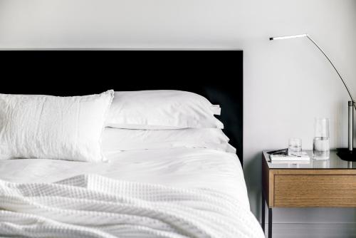 a white bed with a black headboard and a night stand at The Como Melbourne in Melbourne