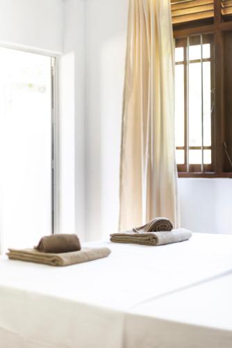 two towels sitting on a counter in front of a mirror at MAKAI Surf House in Ahangama
