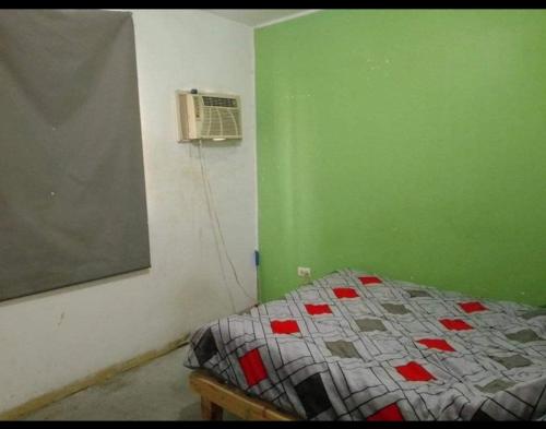 - une chambre avec un lit et un mur vert dans l'établissement Martyshouse, à Poza Rica de Hidalgo