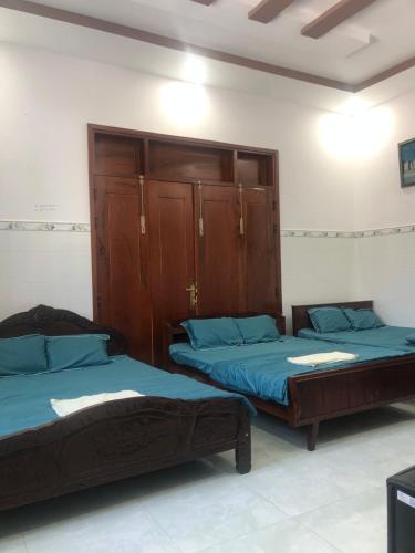 a bedroom with two beds and a wooden cabinet at Khách Sạn Vinhomes Huỳnh Hotel in Ben Tre