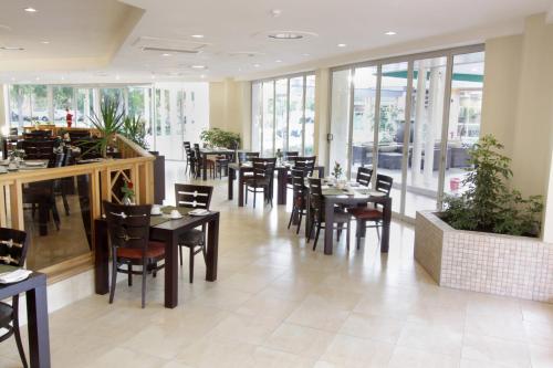 - une salle à manger avec des tables, des chaises et des fenêtres dans l'établissement Cresta Lodge Gaborone, à Gaborone