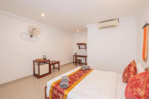 a white bedroom with a bed and a table at Lotus Bleu Guest House in Phumi Ta Phul