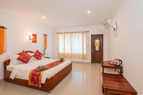 a bedroom with a large bed and a table at Lotus Bleu Guest House in Phumi Ta Phul