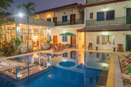 a house with a swimming pool in front of a house at Lotus Bleu Guest House in Phumi Ta Phul
