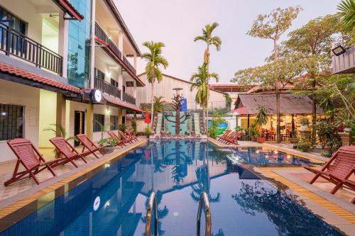 a pool with chairs and a fountain in a courtyard at Lotus Bleu Guest House in Phumi Ta Phul