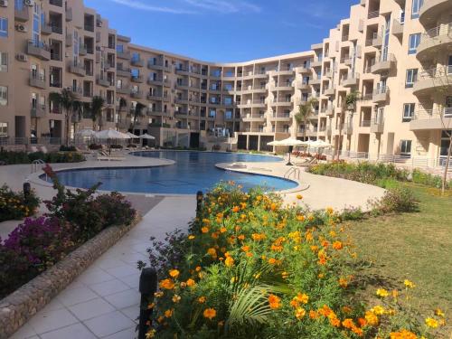 een groot appartementencomplex met een zwembad en bloemen bij Apartman Princess 148a in Hurghada