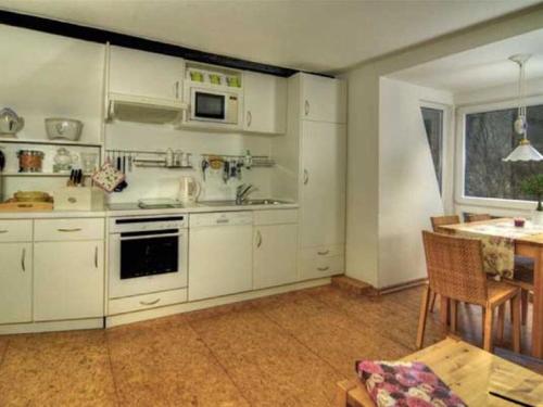 a kitchen with white cabinets and a table in it at Cosy apartment in Harz in Schauenburg