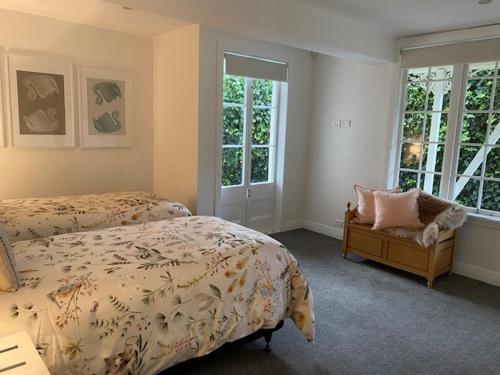 a bedroom with two beds and a chair and windows at Thornleigh in Auckland