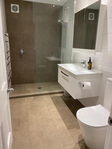 a bathroom with a shower and a toilet and a sink at Thornleigh in Auckland