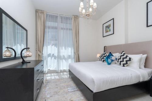 a bedroom with a bed and a dresser and a mirror at Trinity Holiday Homes - Polo Residences Meydan in Dubai