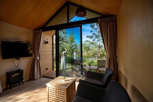 a living room with a large window and a tv at Thara Dara Khaoyai in Ban Tha Maprang