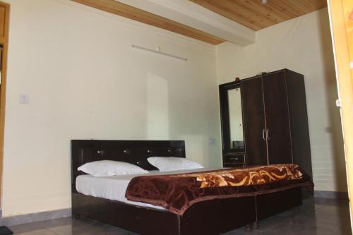 a bedroom with a bed and a cabinet and a mirror at MoonLight Guest House in Kasol