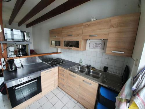 Elle comprend une petite cuisine avec des placards en bois et un évier. dans l'établissement Maison dans un quartier calme, terrain, wifi, télé, à Saint-Nicolas-du-Pélem