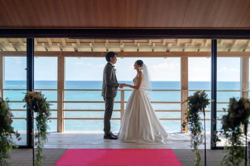 a bride and groom standing in front of a window at Hyakunagaran in Nanjo