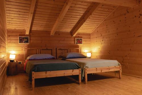 2 camas en una habitación con paredes de madera en B&B Mappamundi, en San Benedetto Val di Sambro