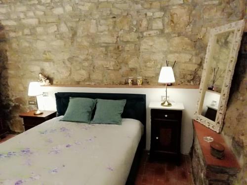 a bedroom with a bed and a stone wall at Iris nel Borgo in Greve in Chianti