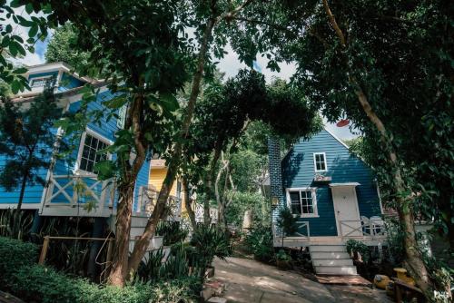 una casa azul con árboles delante de ella en Suriyan Villa Erawan Kanchanaburi สุริยัน วิลล่า เอราวัณ กาญจนบุรี, en Tha Kradan