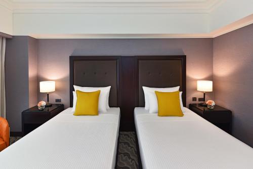 two beds in a hotel room with yellow pillows at Fullon Poshtel - Linkou in Guishan