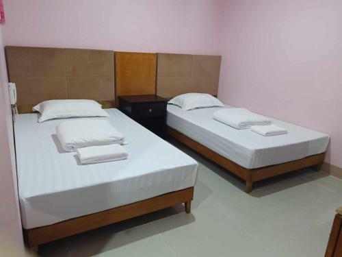 Deux lits jumeaux dans une chambre avec des lictslictslictstritistes dans l'établissement Asia Novo Boutique Hotel - Daet, à Daet