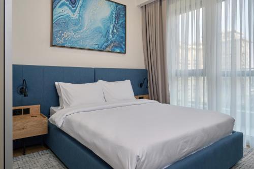 a bedroom with a blue and white bed and a window at STYLO Residences & Suites in Tashkent