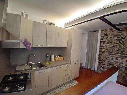 a kitchen with white cabinets and a stone wall at Casa Longhi in Orta San Giulio