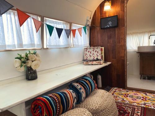 a living room with a bench and windows with flags at BeachBoys - Retro Caravan AirStream in Jeju