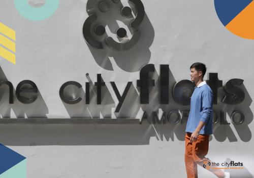 a man walking in front of a wall with a sign at The City Flats Amorsolo in Manila