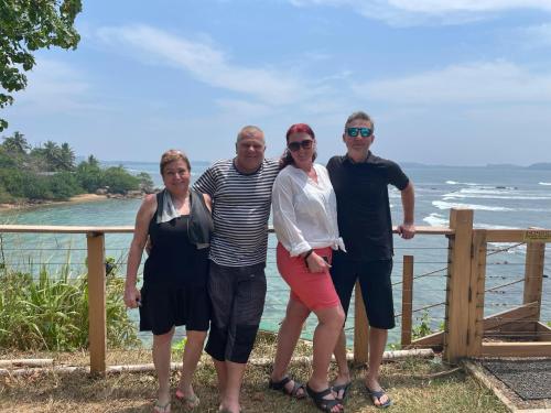 a group of people standing in front of the ocean at Kenno's Korner in Weligama