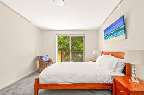 un dormitorio con una cama y una ventana en Surf at Avalon Beach and Laze on the Private Terrace, en Avalon