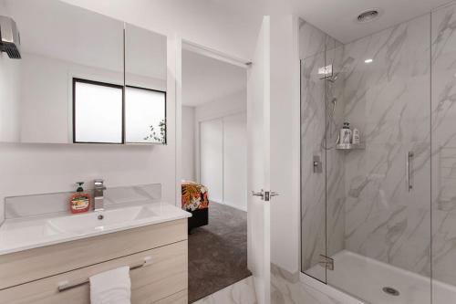 a white bathroom with a shower and a sink at New 2Bdrm 2Brm Hospital CBD Hagley Park Locationn in Christchurch