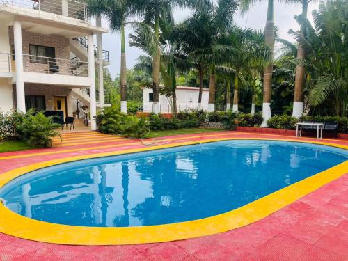 a large swimming pool in a resort with palm trees at Raghuraj Enclave (AAI Farmhouse) in Alibag