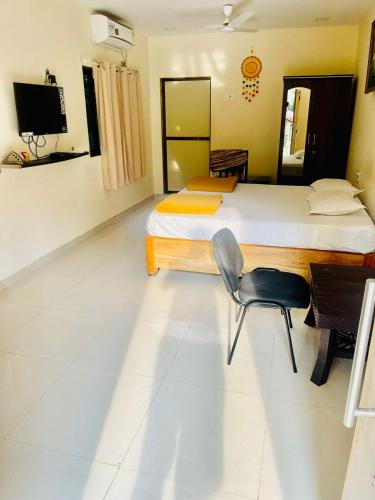 a bedroom with two beds and a chair in it at Raghuraj Enclave (AAI Farmhouse) in Alibag
