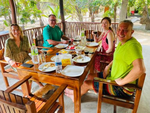 a group of people sitting around a wooden table at Eco Aloevera Garden in Pottuvil