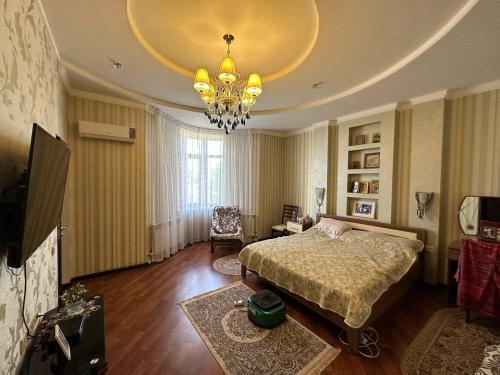 sypialnia z łóżkiem i żyrandolem w obiekcie Saule Guest House w mieście Szymkent