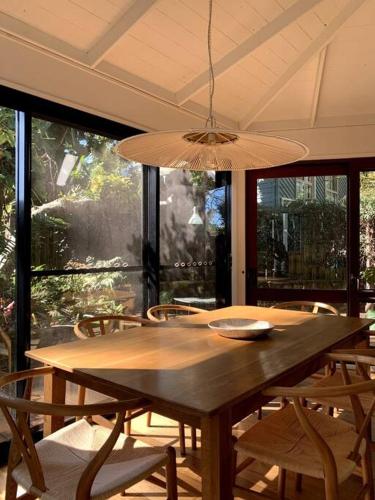 a dining room table with chairs and a chandelier at The Tree House Byron Bay in Byron Bay