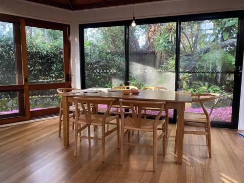 a dining room table with chairs and a large window at The Tree House Byron Bay in Byron Bay
